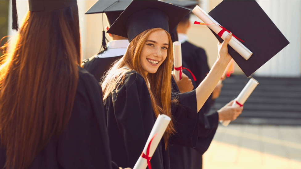Students graduating wearing cap and gown and holding their scrolls